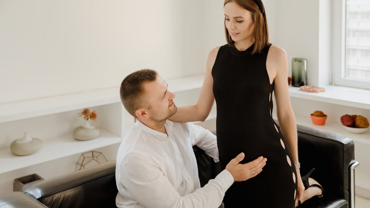 A couple lovingly embraces pregnancy in a modern, serene indoor setting.